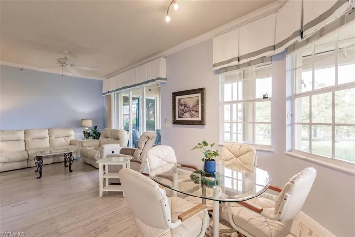 Dining space with crown molding, rail lighting, ceiling fan, and light hardwood / wood-style flooring