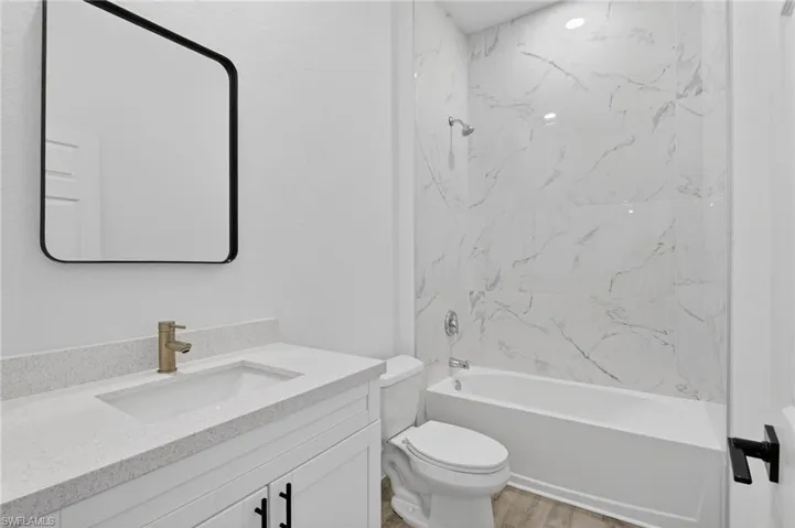 Bathroom featuring vanity, shower / bathtub combination, and light wood-type flooring