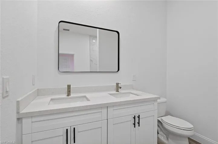 Full bathroom with double vanity and a textured wall