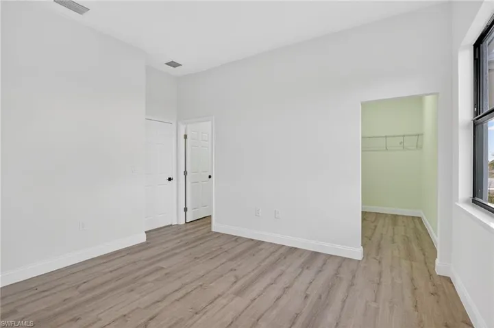 Unfurnished bedroom featuring a spacious closet and light wood-style floors