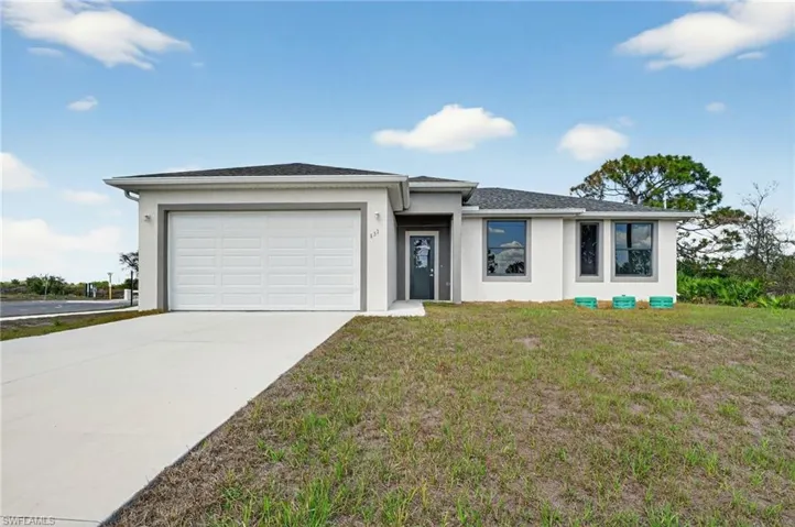 View of front of house with stucco siding, a garage, concrete driveway, and a front yard