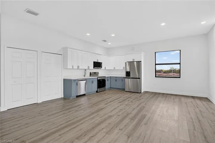 Kitchen featuring stainless steel appliances, light countertops, open floor plan, light wood-style floors, and recessed lighting
