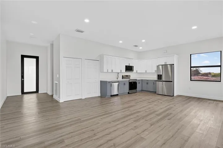 Kitchen featuring open floor plan, light countertops, stainless steel appliances, recessed lighting, and white cabinetry