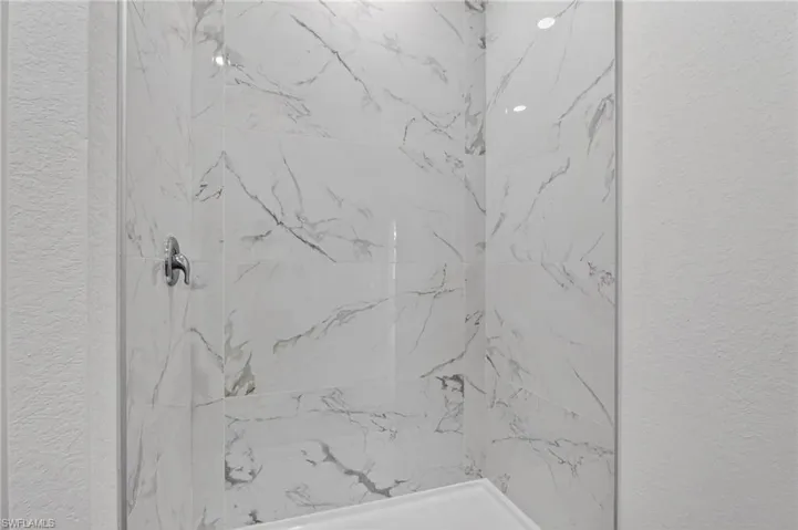 Full bath featuring a textured wall and a marble finish shower