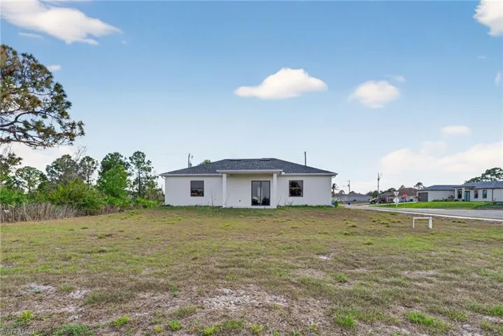 Back of property with stucco siding and a yard