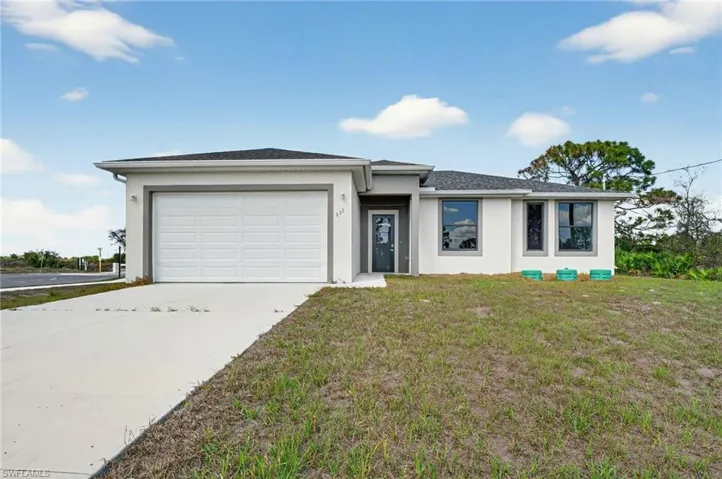 View of front of home featuring stucco siding, an attached garage, a front lawn, and concrete driveway