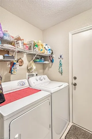 Washroom featuring washing machine and dryer, a textured ceiling, a textured wall, and laundry area