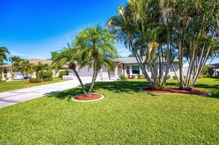 View of front of house featuring a front yard, an attached garage, stucco siding, and concrete driveway