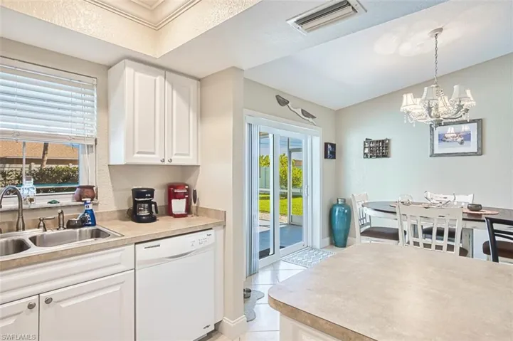 Kitchen with a sink, a chandelier, white dishwasher, visible vents, and white cabinets