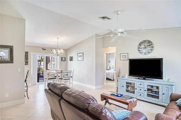 Living room featuring baseboards, lofted ceiling, visible vents, and light tile patterned floors