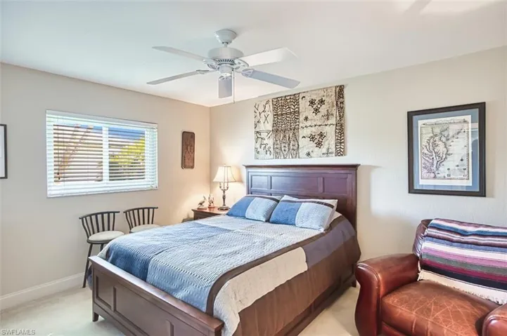 Bedroom with a ceiling fan, light carpet, and baseboards
