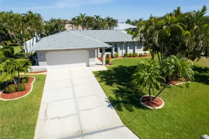 Ranch-style house with an attached garage, concrete driveway, a front yard, roof with shingles, and stucco siding