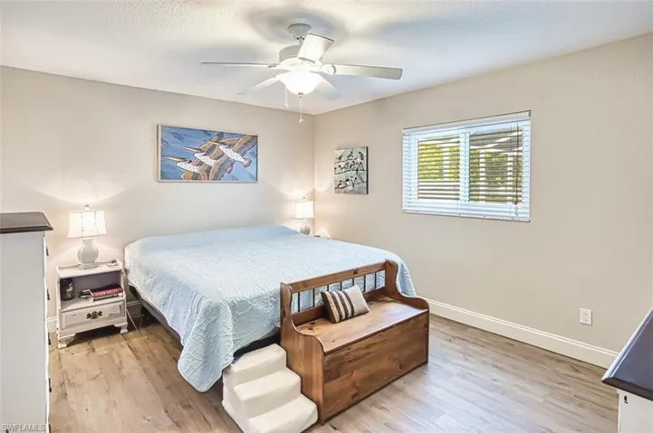 Bedroom featuring baseboards, a textured ceiling, wood finished floors, and a ceiling fan