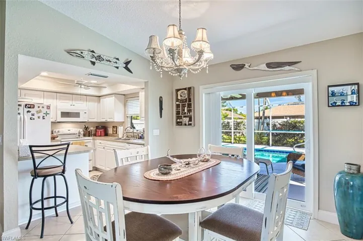 Dining area featuring light tile patterned floors, ceiling fan with notable chandelier, a tray ceiling, and a textured ceiling