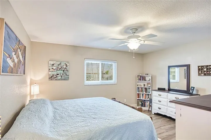 Bedroom with light wood-style floors, ceiling fan, and a textured ceiling