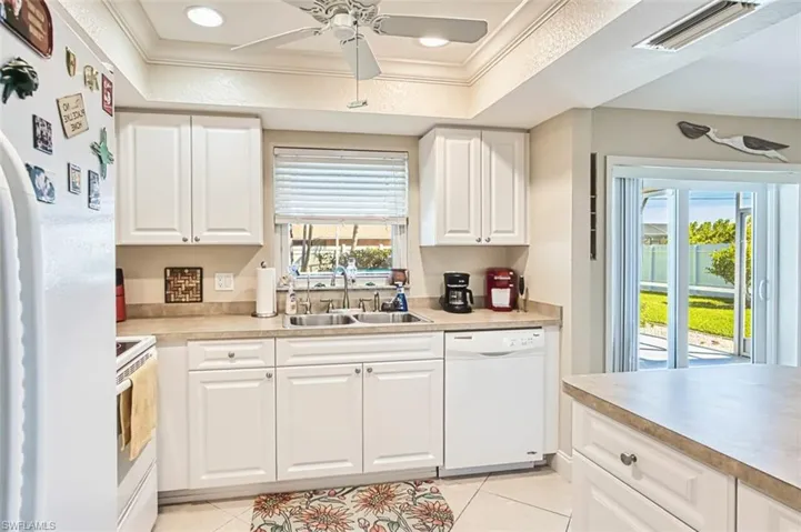 Kitchen with white appliances, visible vents, ornamental molding, and a sink