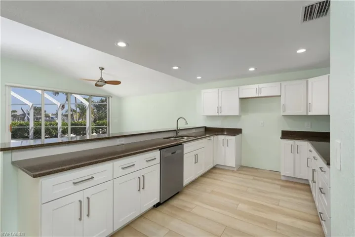 Kitchen with stainless steel dishwasher, white cabinets, a sink, visible vents, and a ceiling fan