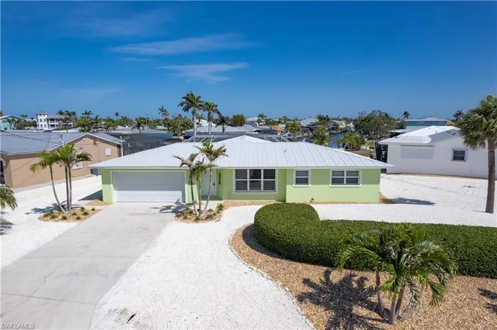 Ranch-style home with a garage, stucco siding, metal roof, and concrete driveway