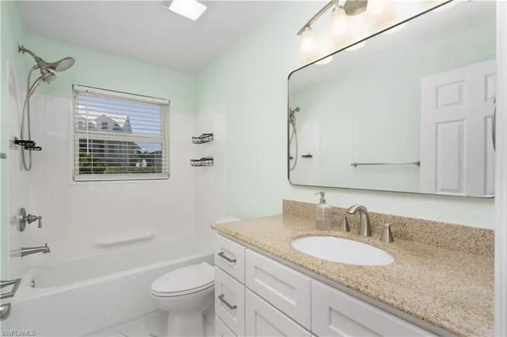 Bathroom featuring marble tile finish floor, toilet, shower / bathtub combination, and vanity.