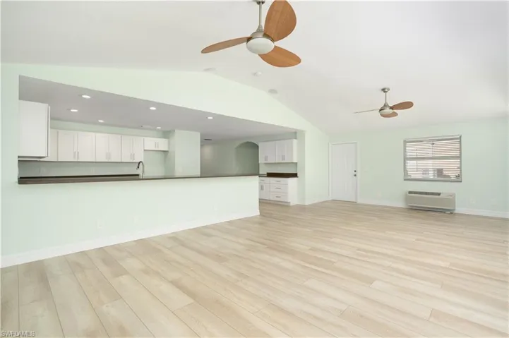 Living room with ceiling fan, light vinyl wood-style floors, lofted ceiling.