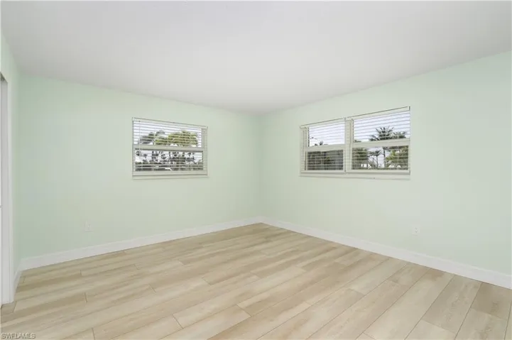 Bedroom with baseboards,  vinyl wood finished floors, and a healthy amount of sunlight