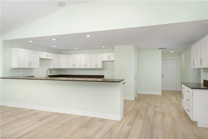 Kitchen with dark countertops, light wood finished floors, and white cabinetry.