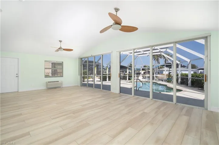 Unfurnished sunroom with a ceiling fan and an AC wall unit