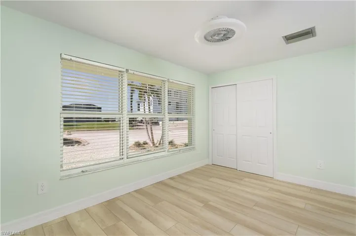 Bedroom with a closet, vinyl wood finished floors, and fan.