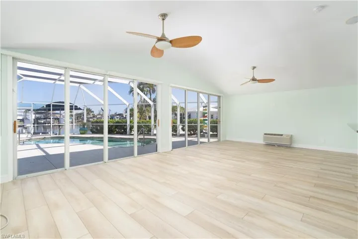 Living room featuring a sunroom, a ceiling fan, vaulted ceiling, and vinyl wood finished floors