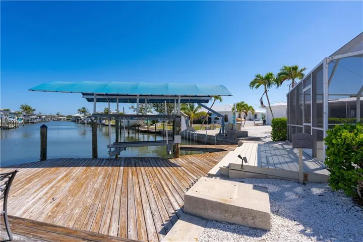 View of dock featuring covered boat lift, a lanai, and a water view