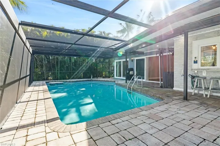 View of pool with glass enclosure and a patio area