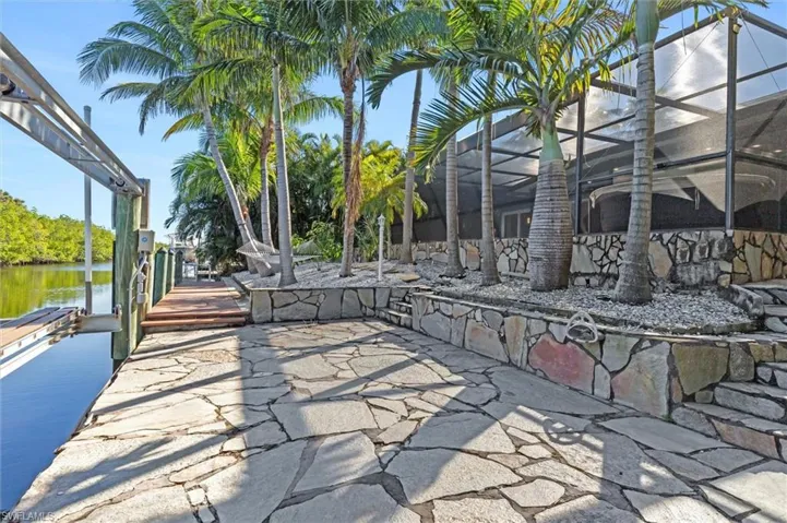View of patio / terrace featuring a boat dock, a water view, and glass enclosure