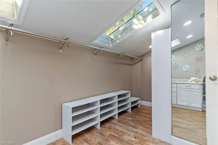 Walk in closet with light hardwood / wood-style flooring