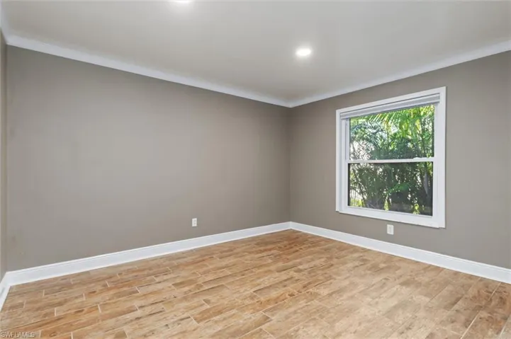 Empty room with light hardwood / wood-style floors and crown molding