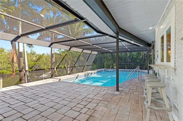 View of swimming pool featuring a water view, a patio area, and a lanai