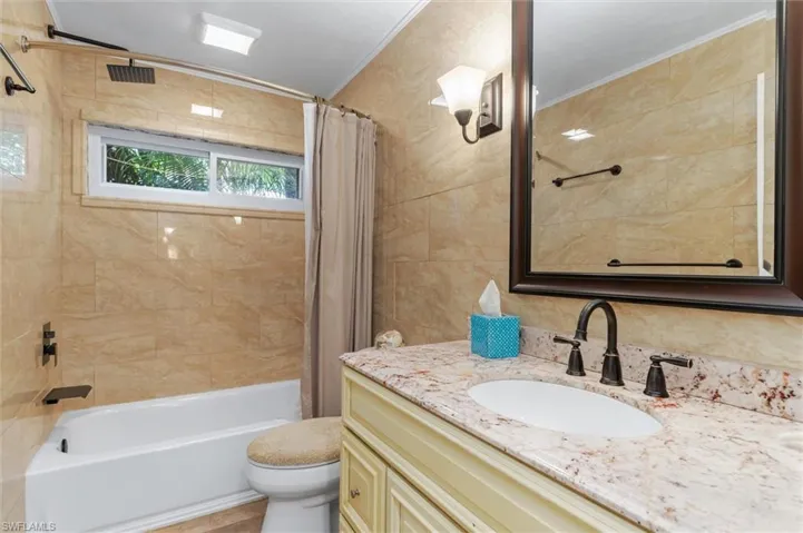 Full bathroom with vanity, toilet, shower / bathtub combination with curtain, and ornamental molding