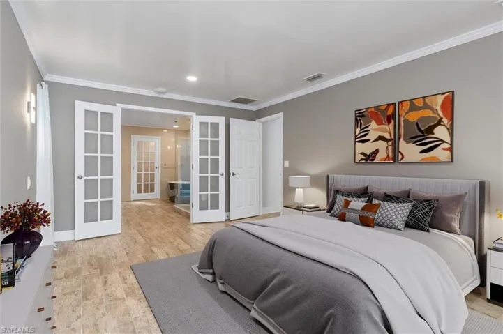 Bedroom featuring light hardwood / wood-style floors, crown molding, and french doors