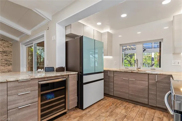 Kitchen with sink, light hardwood / wood-style flooring, a wealth of natural light, stainless steel appliances, and beverage cooler