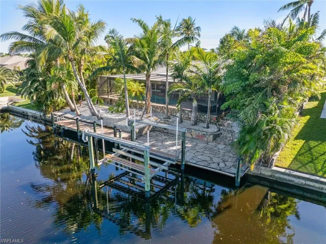 View of dock with a yard, a water view, and a lanai