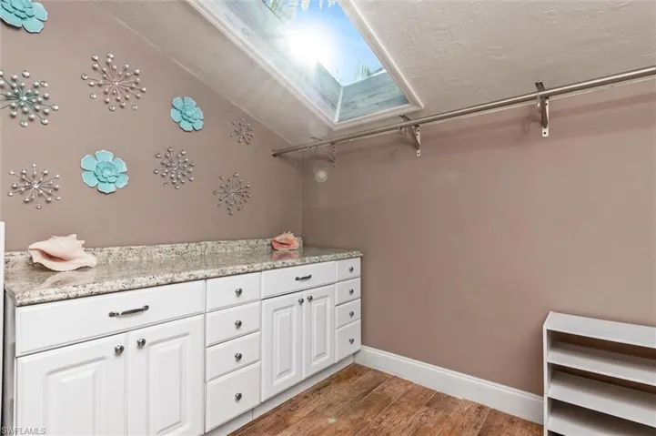 Bathroom featuring vanity, hardwood / wood-style flooring, and vaulted ceiling with skylight