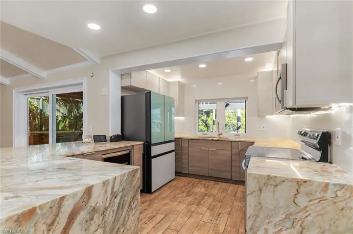 Kitchen with light hardwood / wood-style floors, sink, ornamental molding, and stainless steel appliances
