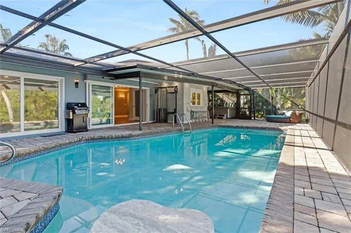 View of pool with a patio, glass enclosure, and area for grilling