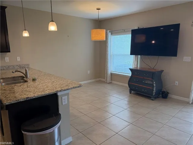 Kitchen featuring light stone countertops, a peninsula, hanging light fixtures, and light tile patterned flooring