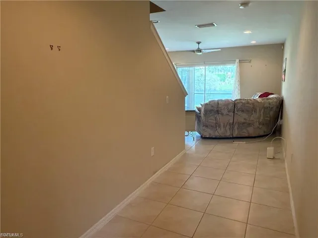 Hallway with light tile patterned flooring and baseboards