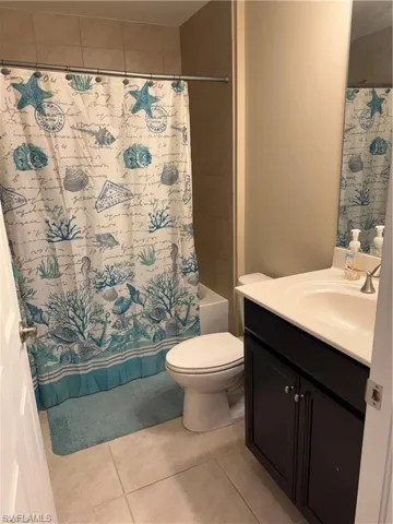 Full bathroom with vanity, light tile patterned floors, and shower / tub combo