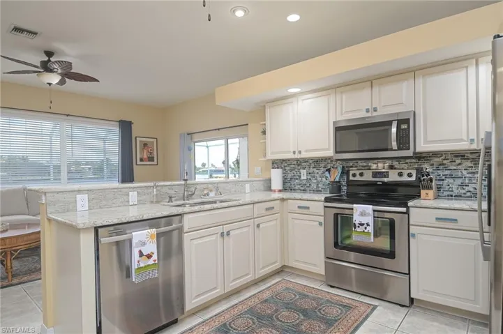 Kitchen featuring appliances with stainless steel finishes, sink, kitchen peninsula, and ceiling fan