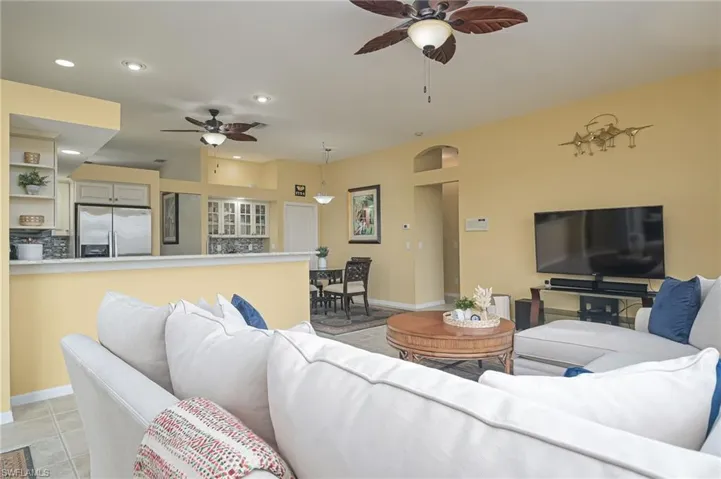 Living room with ceiling fan and light tile floors