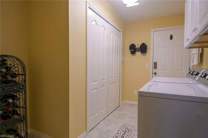 Clothes washing area featuring separate washer and dryer, light tile flooring, and cabinets