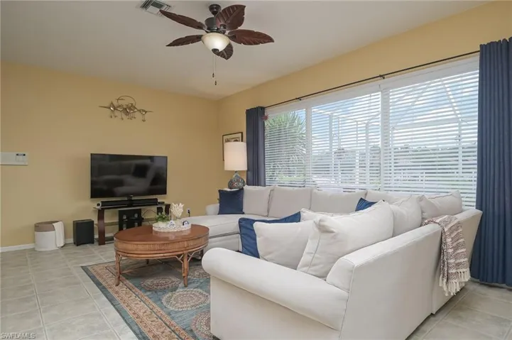 Living room with ceiling fan and light tile floors