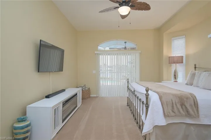 Bedroom with ceiling fan, carpet, multiple windows, and access to exterior